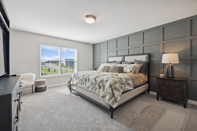 bedroom featuring light carpet, a decorative wall, and a textured ceiling