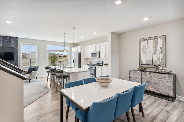 dining space with light wood-style floors, recessed lighting, and baseboards