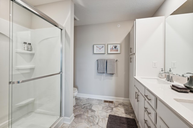 bathroom featuring toilet, a sink, baseboards, a shower stall, and double vanity