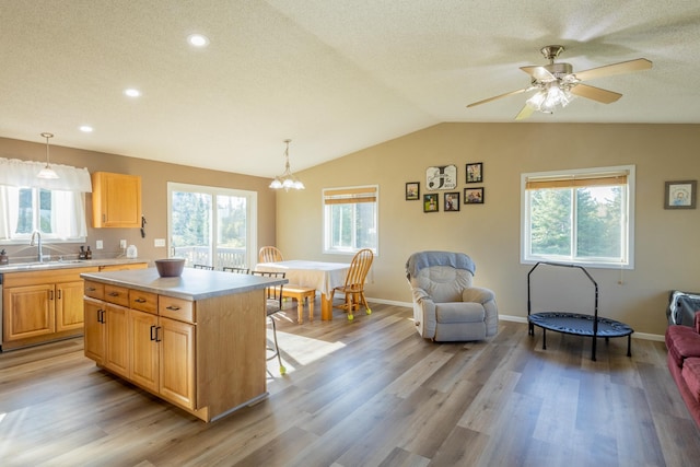 kitchen featuring a kitchen island, light countertops, a sink, and decorative light fixtures