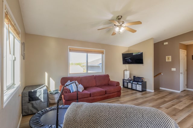 living area featuring ceiling fan, light wood-style flooring, baseboards, and vaulted ceiling