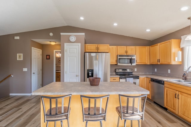 kitchen featuring a kitchen breakfast bar, stainless steel appliances, light countertops, and a center island