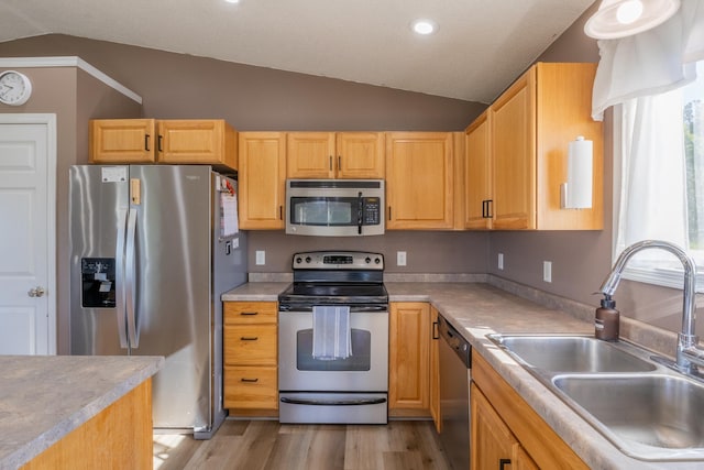 kitchen with lofted ceiling, stainless steel appliances, a sink, light wood-style floors, and light countertops