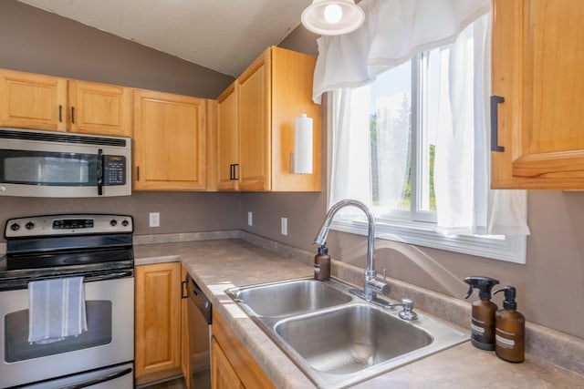 kitchen featuring light brown cabinets, appliances with stainless steel finishes, light countertops, and a sink