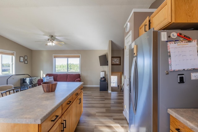 kitchen featuring light brown cabinets, a kitchen island, open floor plan, stainless steel refrigerator with ice dispenser, and light wood finished floors