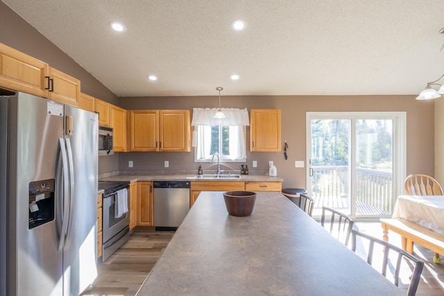 kitchen with hanging light fixtures, light brown cabinets, appliances with stainless steel finishes, and a sink