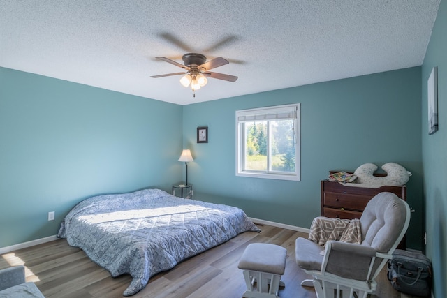 bedroom featuring light wood-style floors, ceiling fan, a textured ceiling, and baseboards