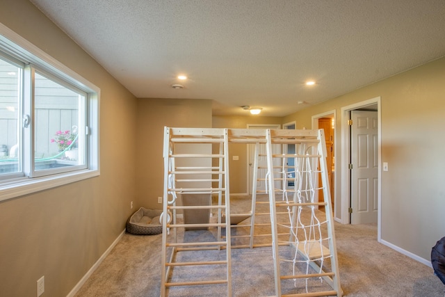 bedroom with carpet floors, baseboards, and a textured ceiling