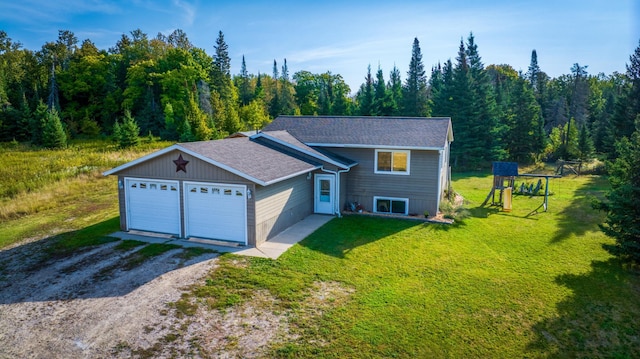 view of front of property featuring driveway, a front lawn, a playground, and a wooded view