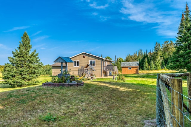 view of yard featuring a shed, fence, a wooden deck, and an outdoor structure