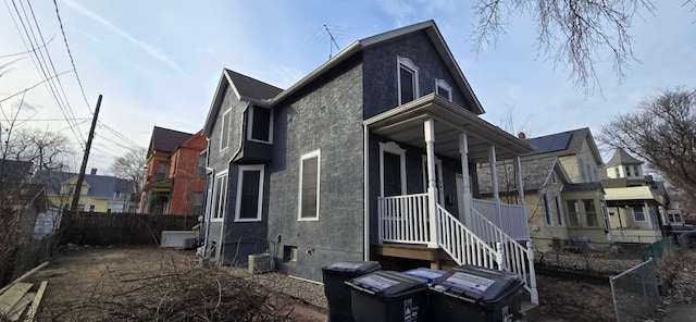 rear view of property featuring fence and stucco siding