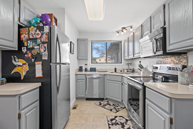 kitchen with visible vents, light countertops, gray cabinets, stainless steel appliances, and a sink