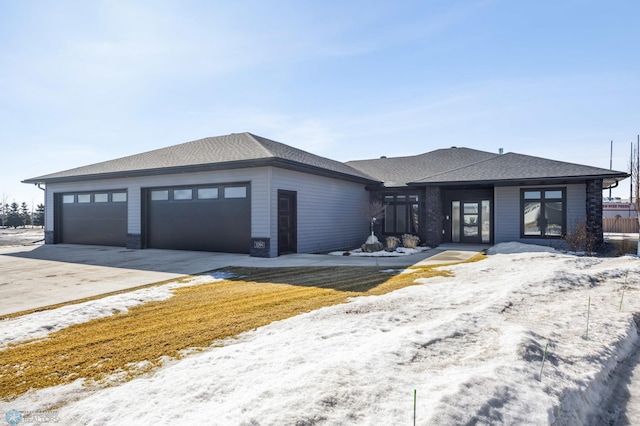 prairie-style house with concrete driveway, roof with shingles, and an attached garage