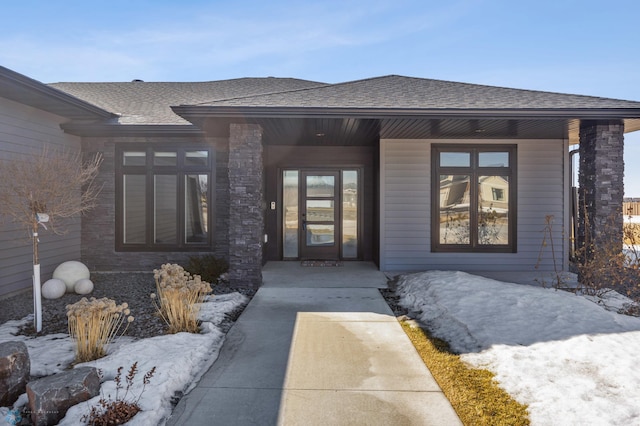 property entrance featuring covered porch and a shingled roof