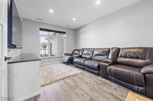 living area with recessed lighting, visible vents, baseboards, and wood finished floors