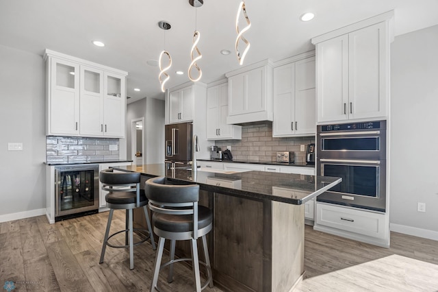 kitchen with beverage cooler, double wall oven, a breakfast bar, and high quality fridge