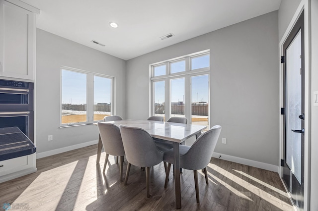 dining room with dark wood-style flooring, visible vents, and baseboards