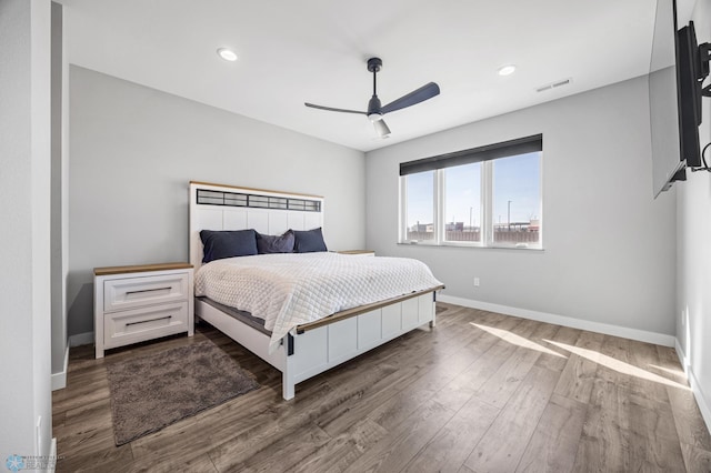 bedroom with ceiling fan, wood finished floors, visible vents, and baseboards