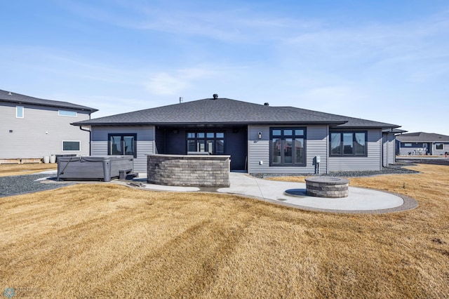 rear view of house featuring a yard, an outdoor fire pit, a patio, and a hot tub