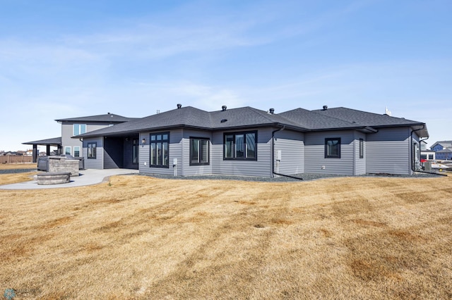 rear view of house featuring a shingled roof, a patio area, and a yard