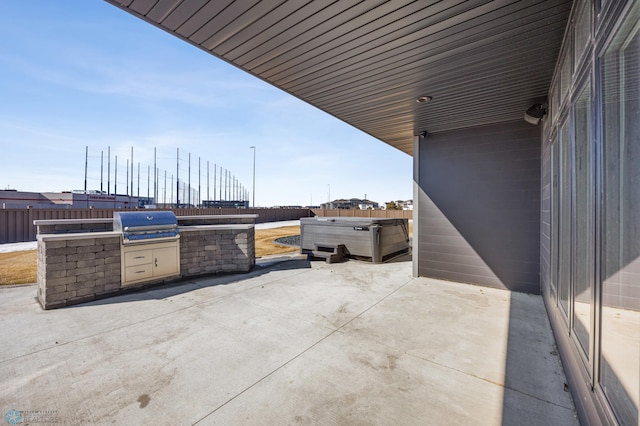 view of patio / terrace featuring a hot tub, a fenced backyard, a grill, and exterior kitchen