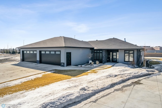 view of front of house featuring a garage, concrete driveway, and roof with shingles