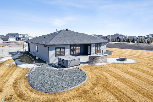 back of property featuring a residential view, a hot tub, a patio, and a fire pit