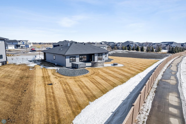 back of house featuring a residential view, fence, and roof with shingles