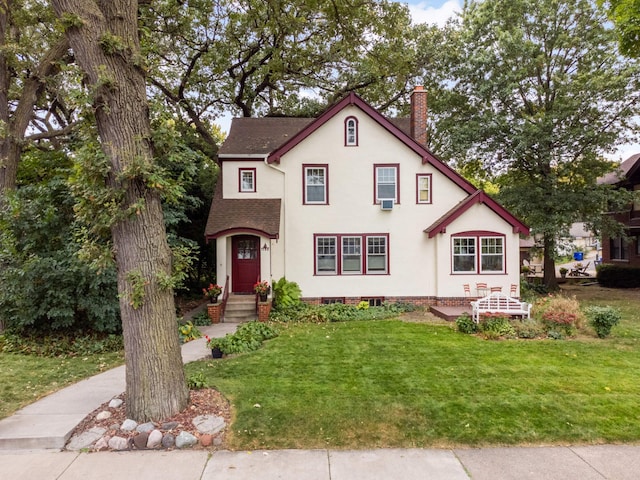 view of front of home featuring a front yard, roof with shingles, a chimney, and stucco siding