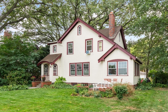 view of front of home featuring a front yard, roof with shingles, a chimney, and stucco siding