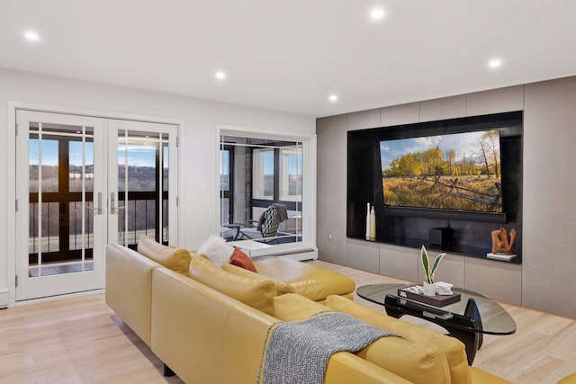 living room with a wealth of natural light, recessed lighting, light wood-style flooring, and french doors
