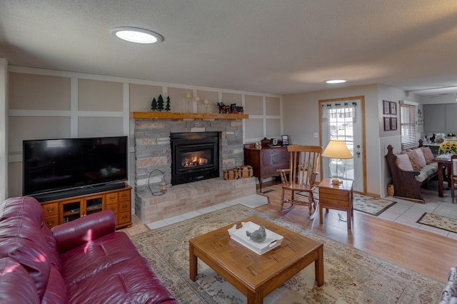 living area featuring built in shelves, a fireplace, a textured ceiling, and wood finished floors