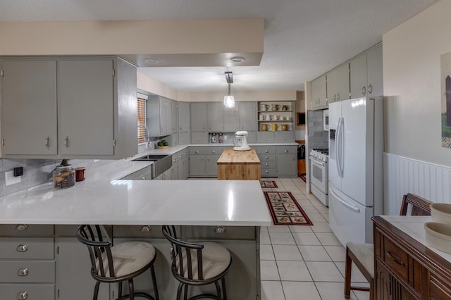 kitchen with a peninsula, white appliances, and gray cabinets