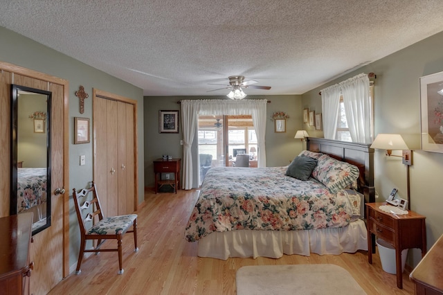 bedroom with a textured ceiling, light wood finished floors, multiple windows, and a ceiling fan