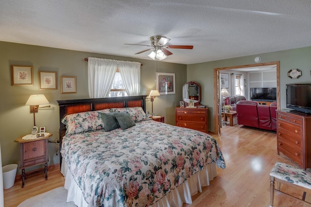 bedroom featuring a ceiling fan, light wood-type flooring, and a textured ceiling