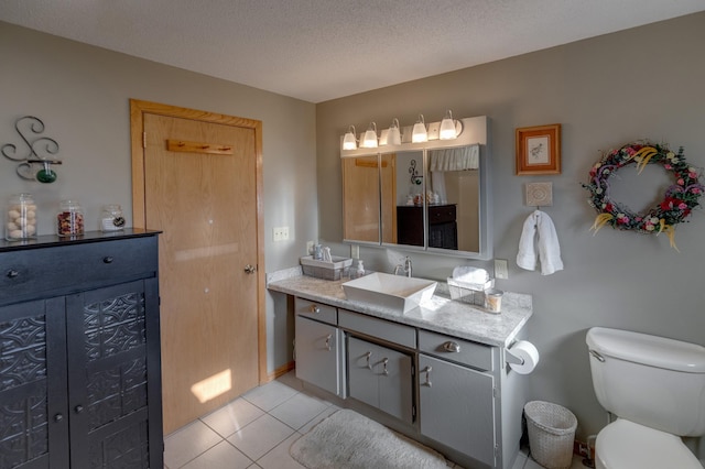 bathroom with toilet, vanity, a textured ceiling, and tile patterned floors