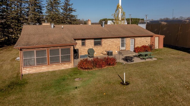 back of property featuring a shingled roof, brick siding, and a lawn