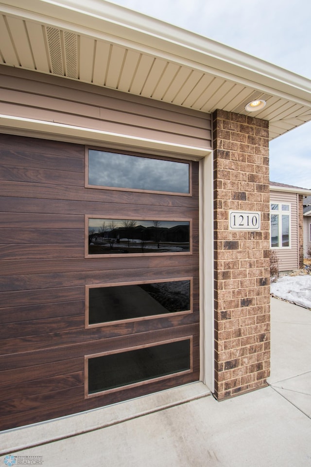 view of exterior entry with a garage and brick siding