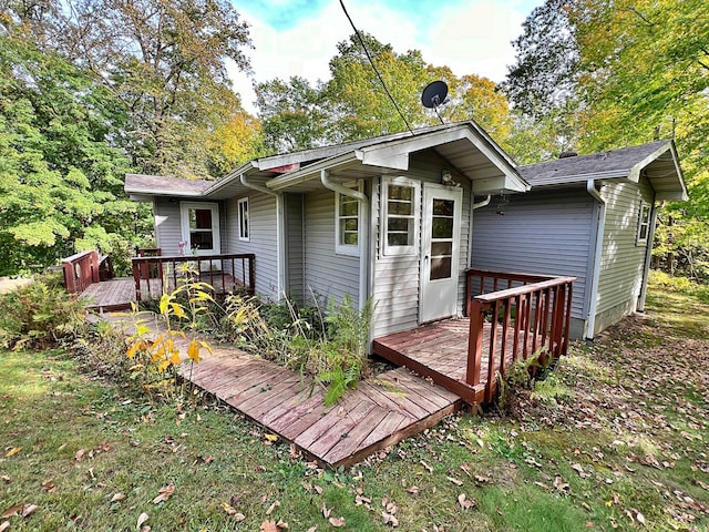 rear view of house with a lawn and a wooden deck