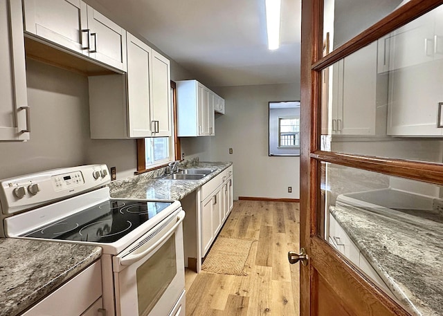 kitchen with a sink, stone countertops, white cabinetry, and white electric range