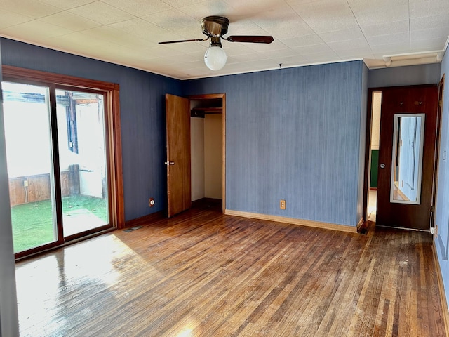 spare room with a ceiling fan, dark wood-style flooring, and baseboards