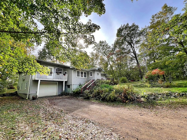 view of front of property featuring dirt driveway, stairway, an attached garage, and a wooden deck