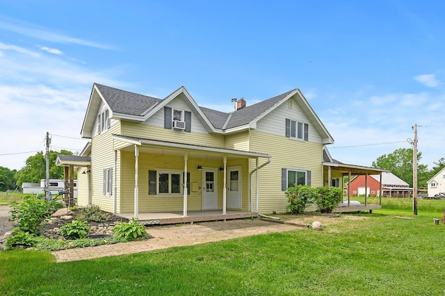 view of front of house with a shingled roof, cooling unit, covered porch, and a front lawn