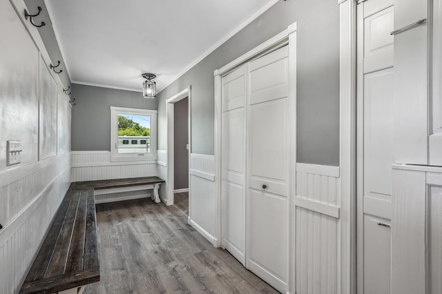 corridor featuring a wainscoted wall, wood finished floors, and crown molding