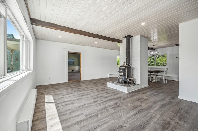 unfurnished living room featuring a wood stove, beamed ceiling, and wood finished floors