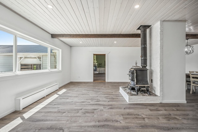 unfurnished living room featuring recessed lighting, baseboard heating, a wood stove, wood finished floors, and beamed ceiling