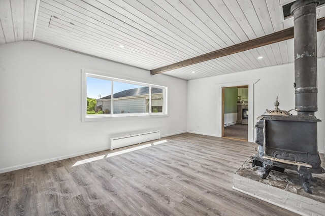 unfurnished living room featuring a wood stove, a baseboard radiator, baseboards, and wood finished floors