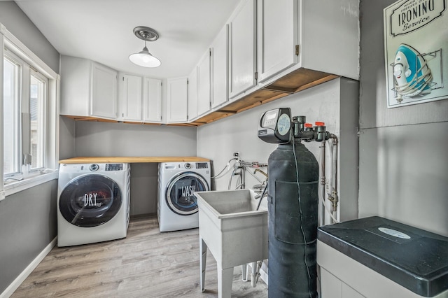 laundry room with light wood-style flooring, washing machine and clothes dryer, cabinet space, and baseboards