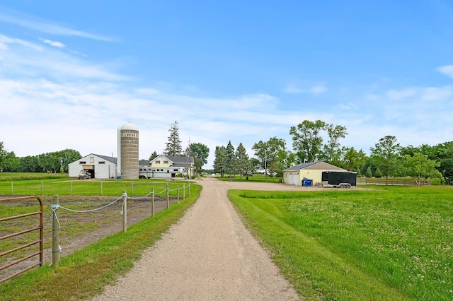 view of street with dirt driveway and a rural view