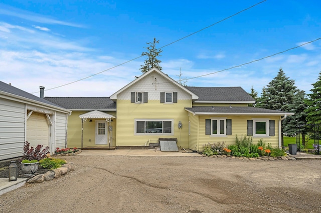 view of front facade featuring a garage, roof with shingles, and driveway